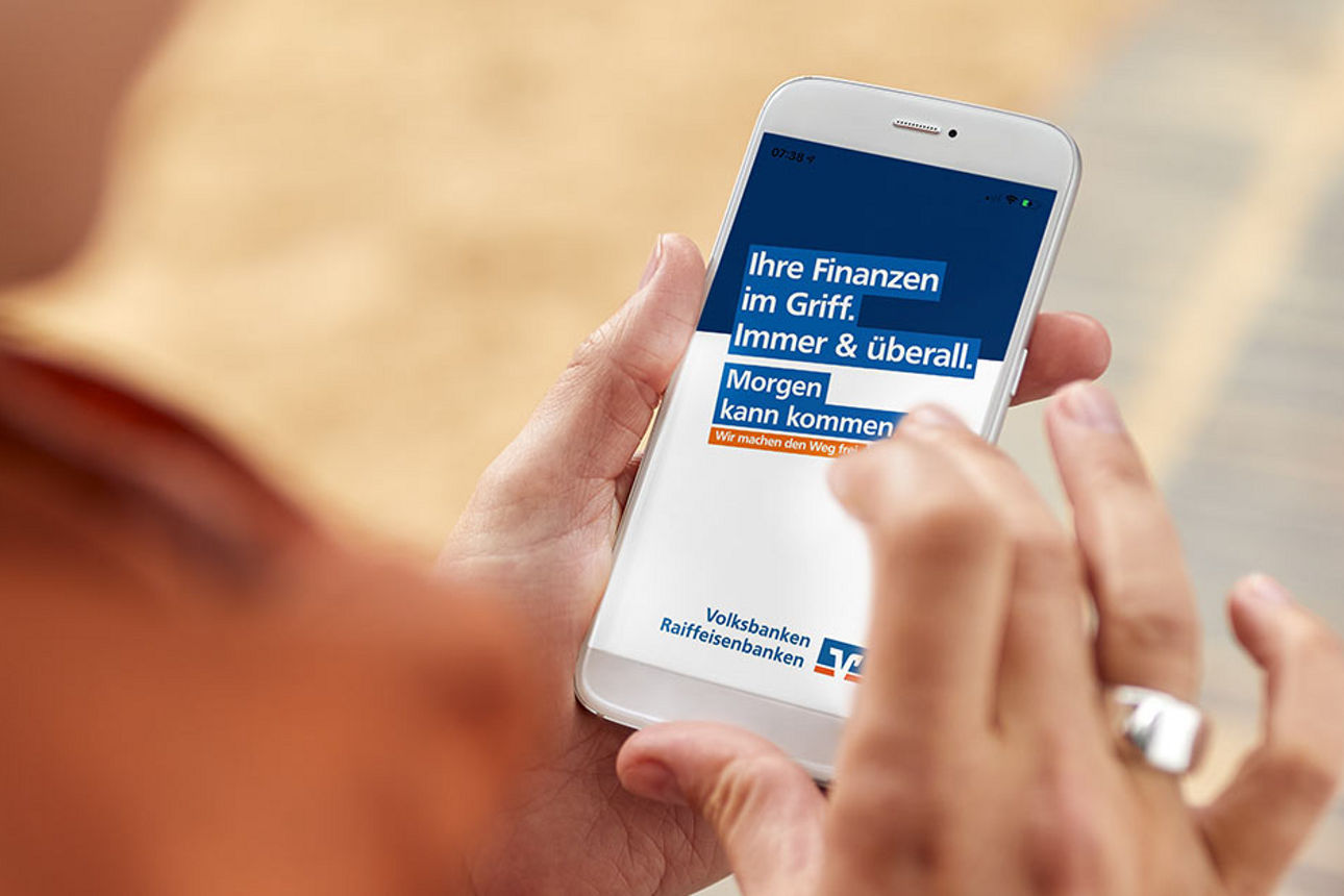 Frau mit Handy in der Hand steht in der Fußgängerzone