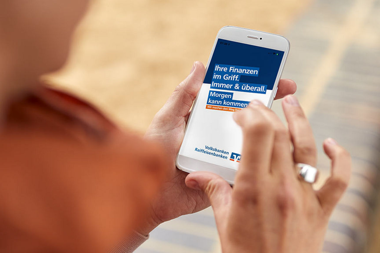Frau guckt sich ein Bild auf Ihrem Handy zu Finanzen im Griff der Volks- und Raiffeisenbank an