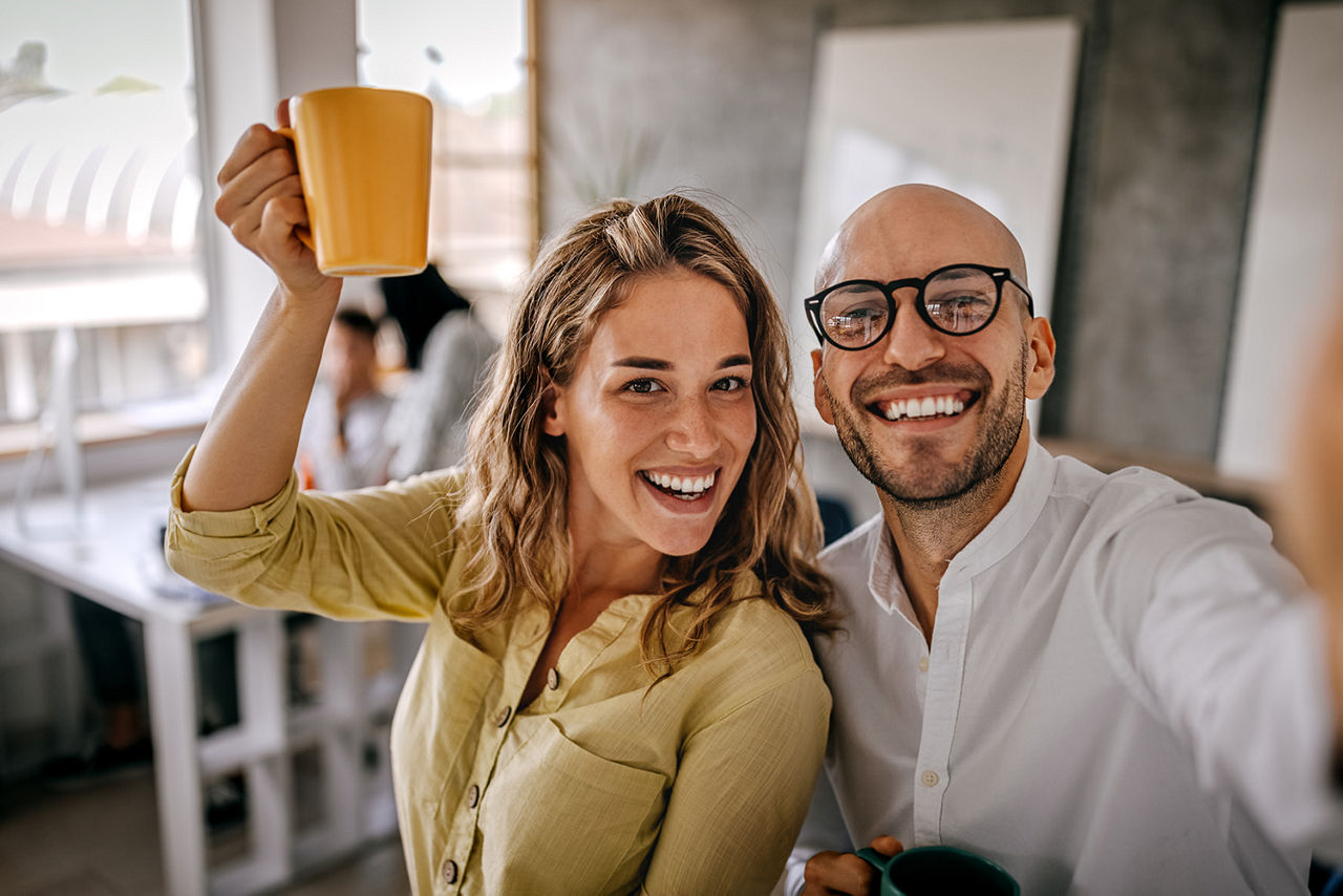 Kollegen machen ein Selfie mit der Kaffeetasse im Büro