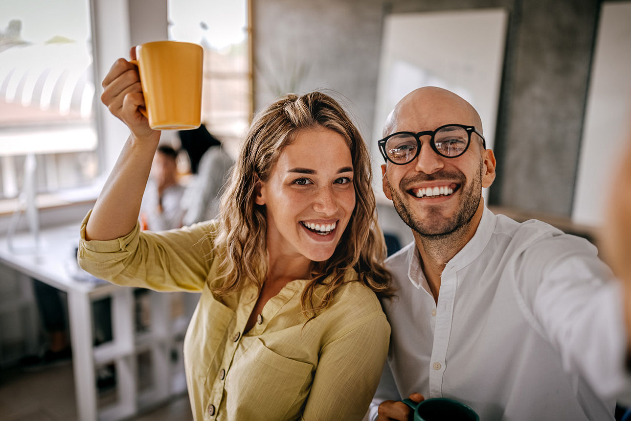 Kollegen machen ein Selfie mit der Kaffeetasse im Büro