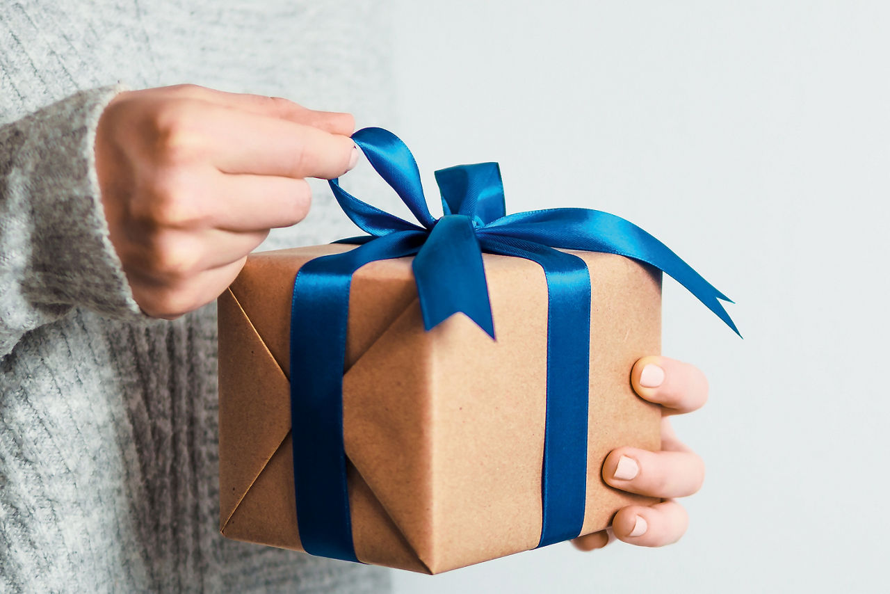 Eine Frau die ein Geschenk in der Hand hält und es auspackt