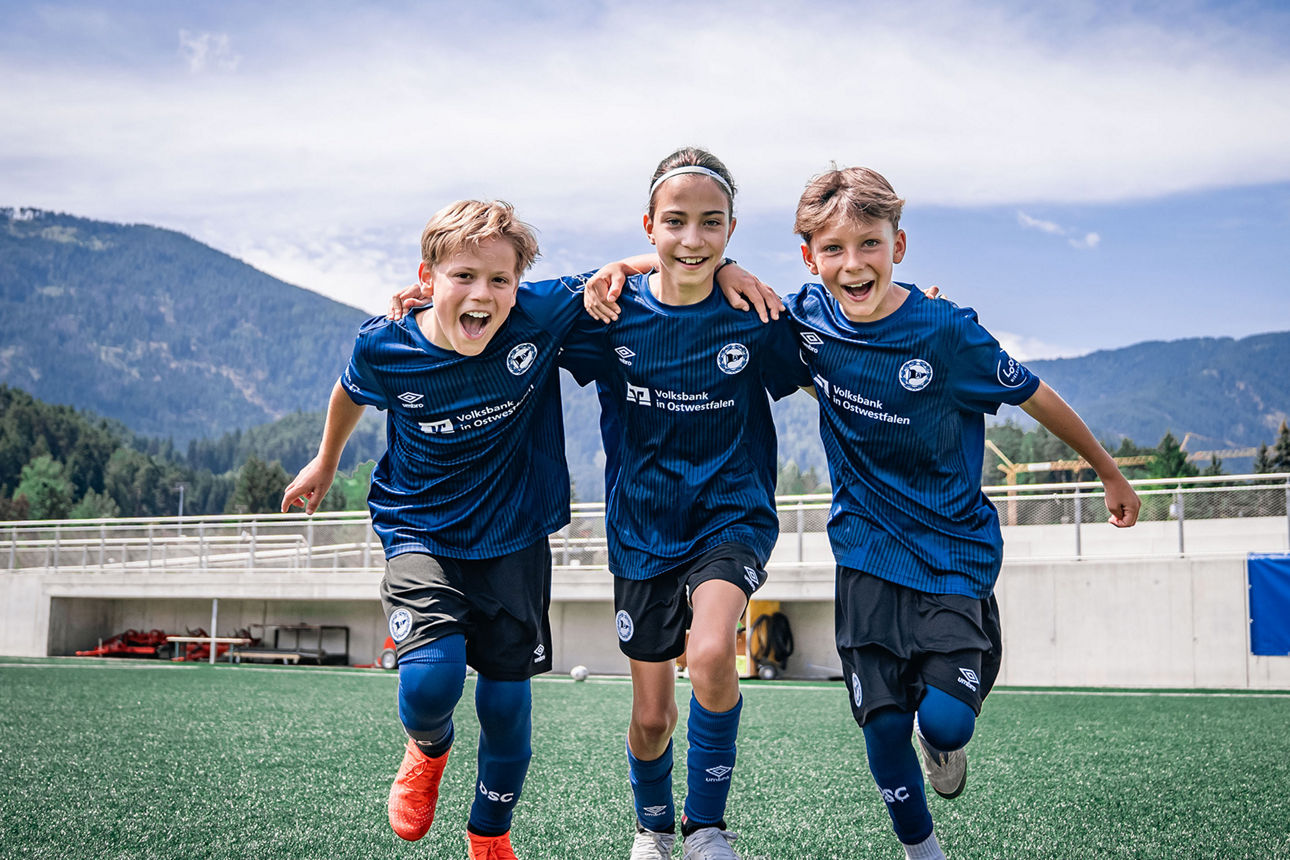 Drei Kinder in Trikots der Arminia Fußballschule