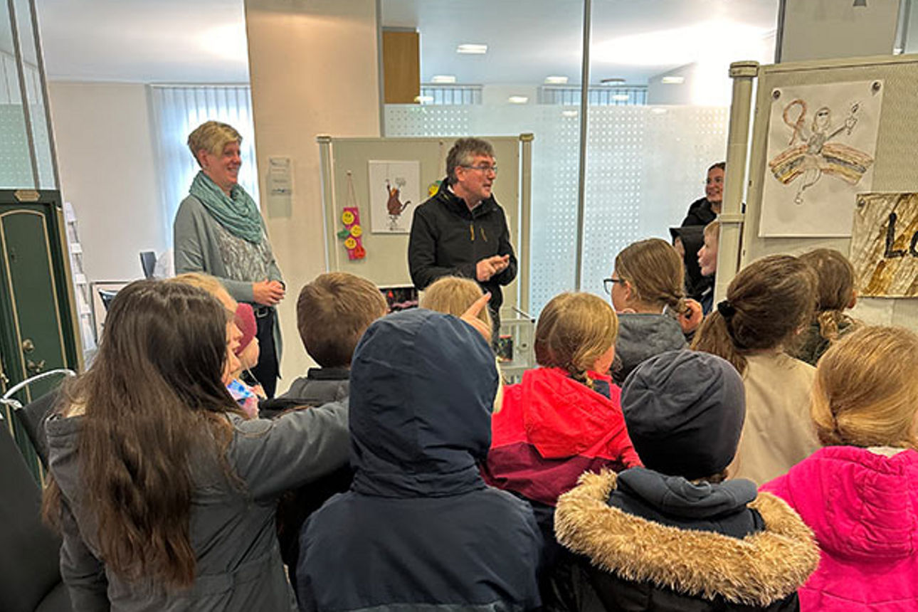 Zwei Erwachsene im Gespräch mit vielen Kindern in der Kunstausstellung