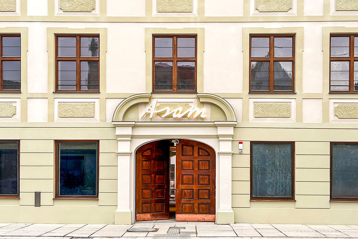 Asamgebäude Freising Blick auf Hausfassade im alten Stil mit Eingangstor aus Holz,darüber Schriftzug "Asam"