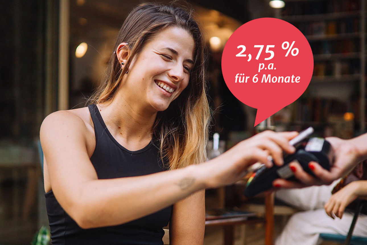 Junge Frau bezahlt auf der Terrasse eines Cafés mit dem Smartphone.
