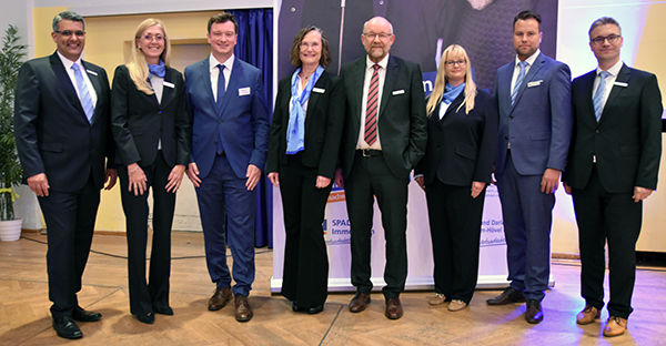 Eine Gruppe von Geschäftsleuten lächelt und posiert gemeinsam für ein formelles Foto. 