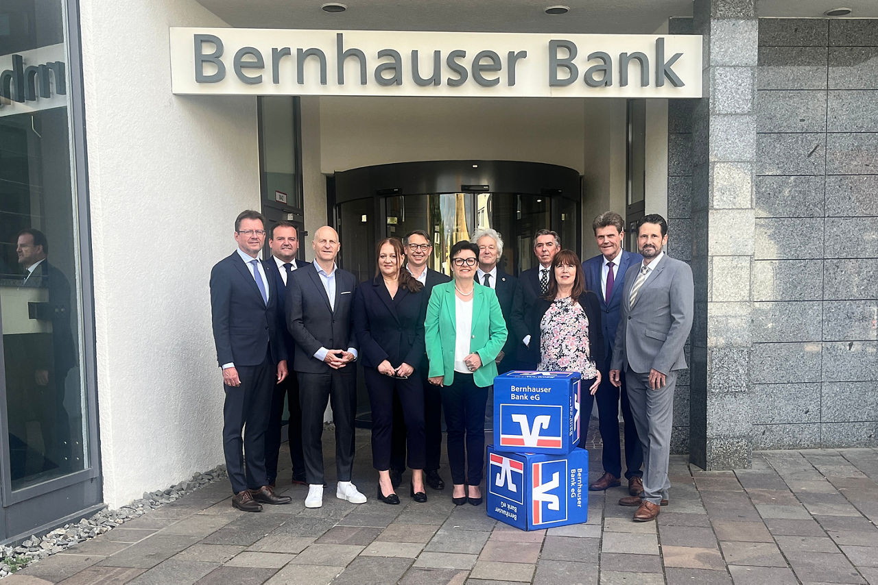 Eine bunte Gruppe von Menschen versammelt sich vor einer Bank