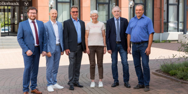 Die Mitglieder des Teams der neuen Hochschule für Technik und Wirtschaft in Köln lächeln in einer gemeinsamen Umgebung.
