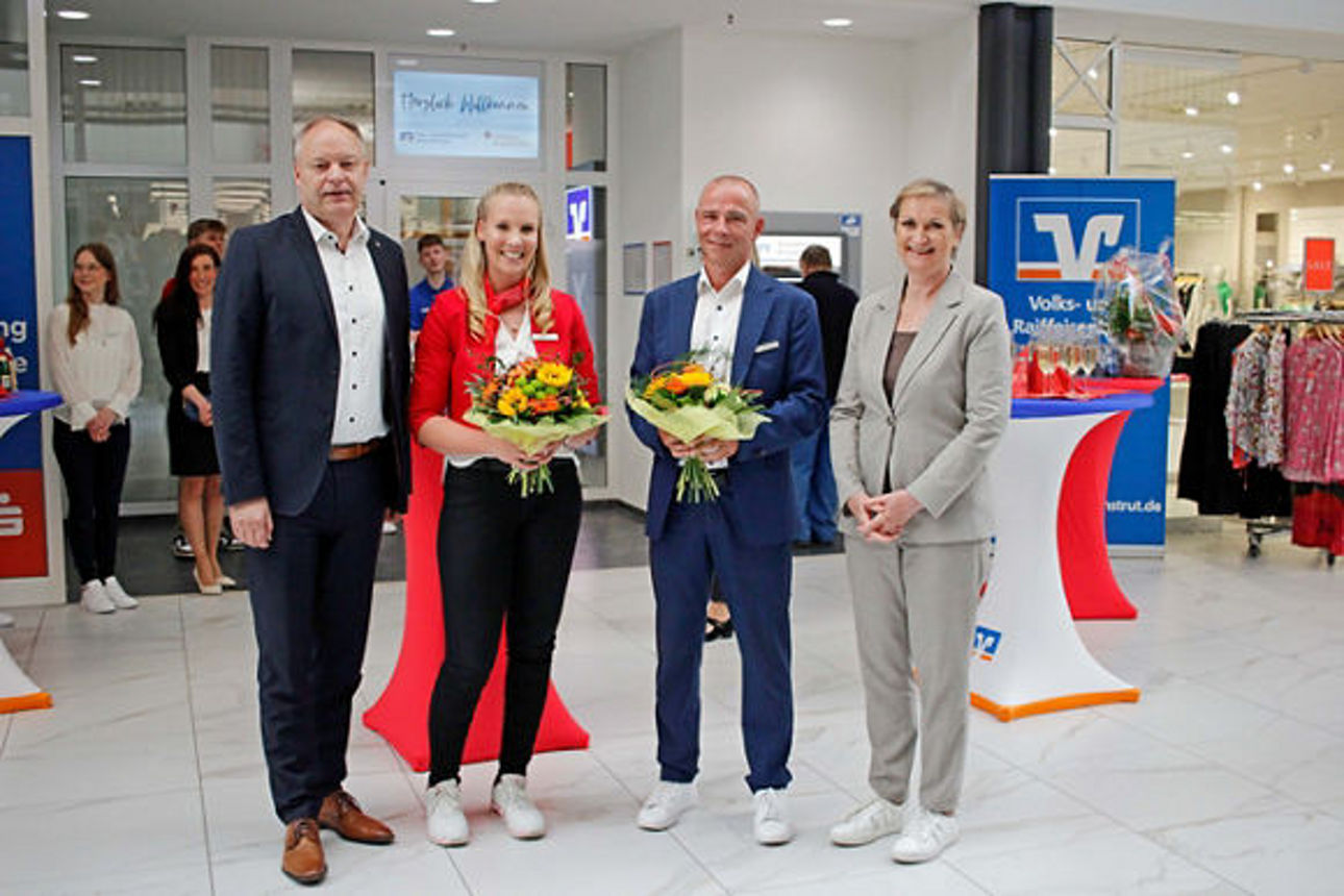 Die Berater der Volksbank und Sparkasse halten Blumensträuße bei der Filialeröffnung in den Händen