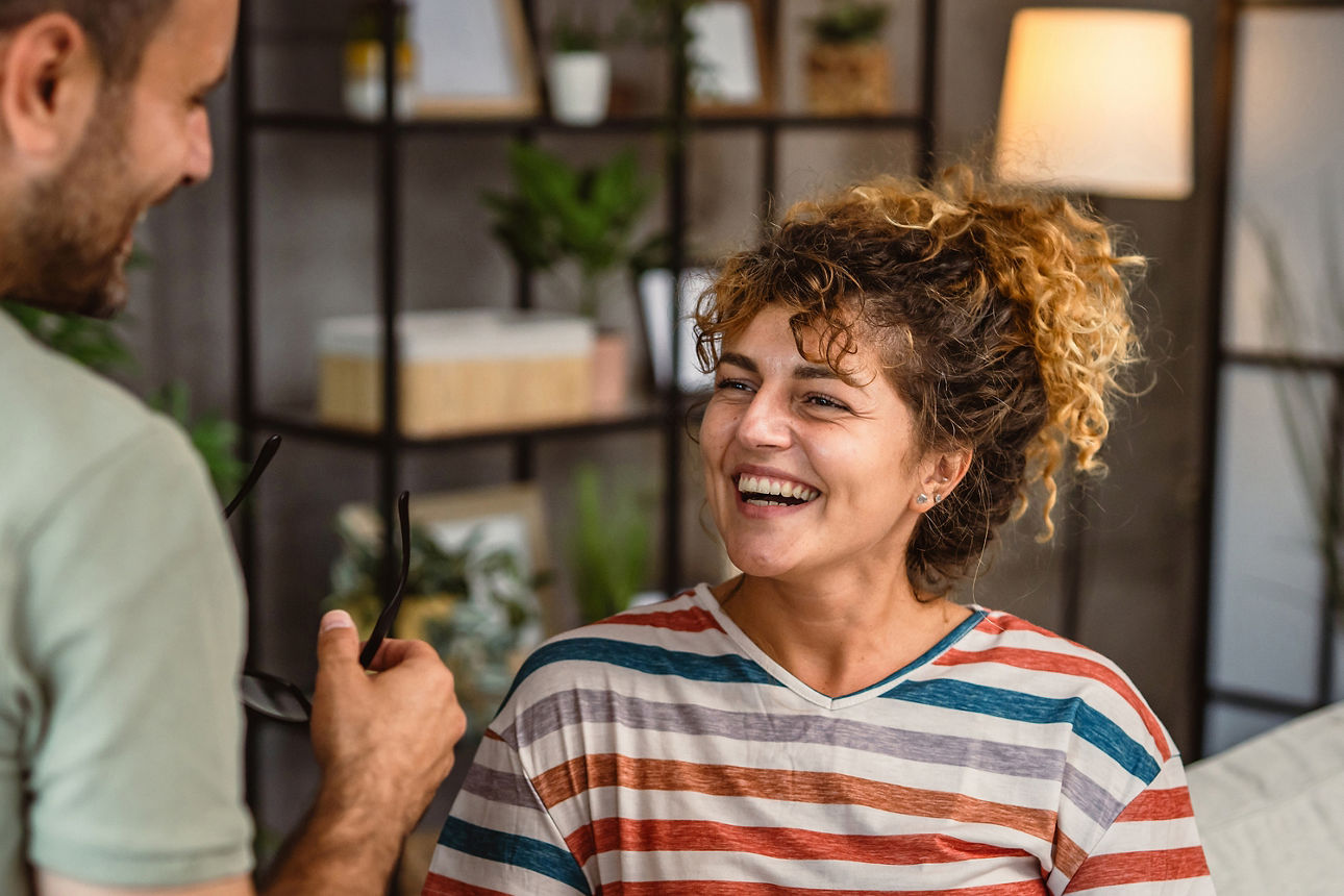 Frau sitzt auf der Couch und lächet einem Mann zu