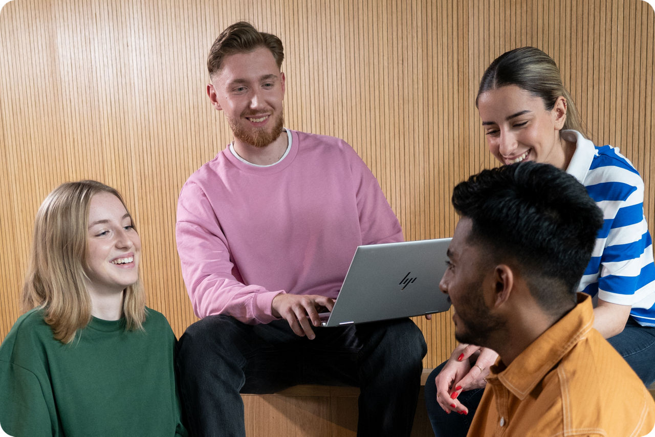Vier junge Menschen sitzen um einen Laptop herum und unterhalten sich