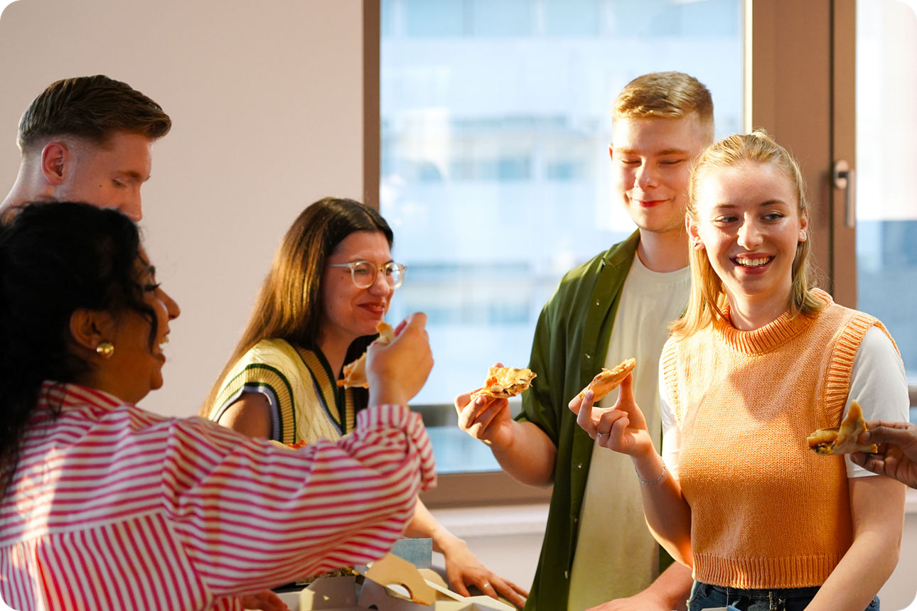 Eine Gruppe Auszubildender isst in der Küche Pizza