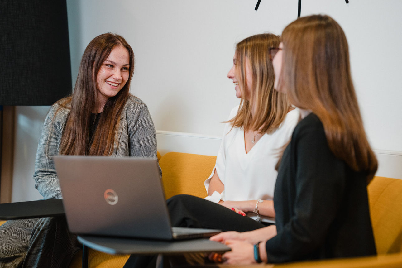 Gruppe lächelnder junger Kollegen, die sich im modernen Büro miteinander unterhalten