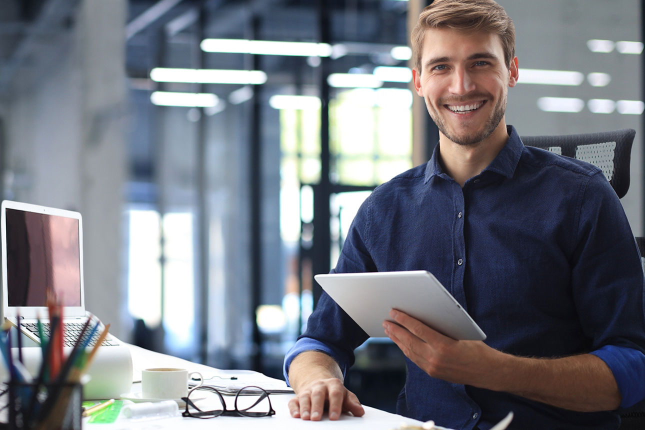 Junger Mann mit Tablet in der Hand lachend in der Kamara