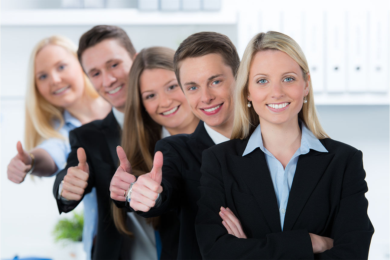 Auzubis die in einer reihe hintereinander mit Daumen hoch stehen. 