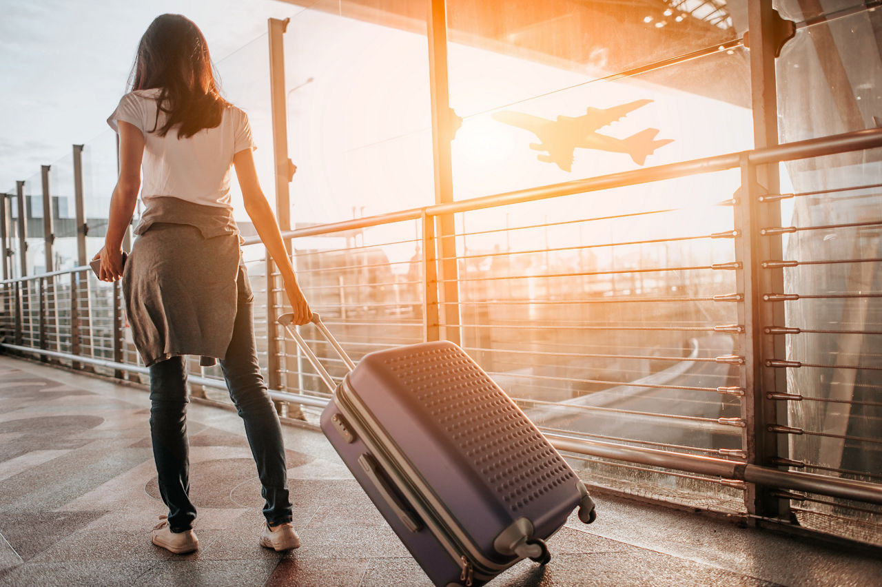 Frau mit Koffer in der Hand läuft am Flughafen zu ihrem Gate