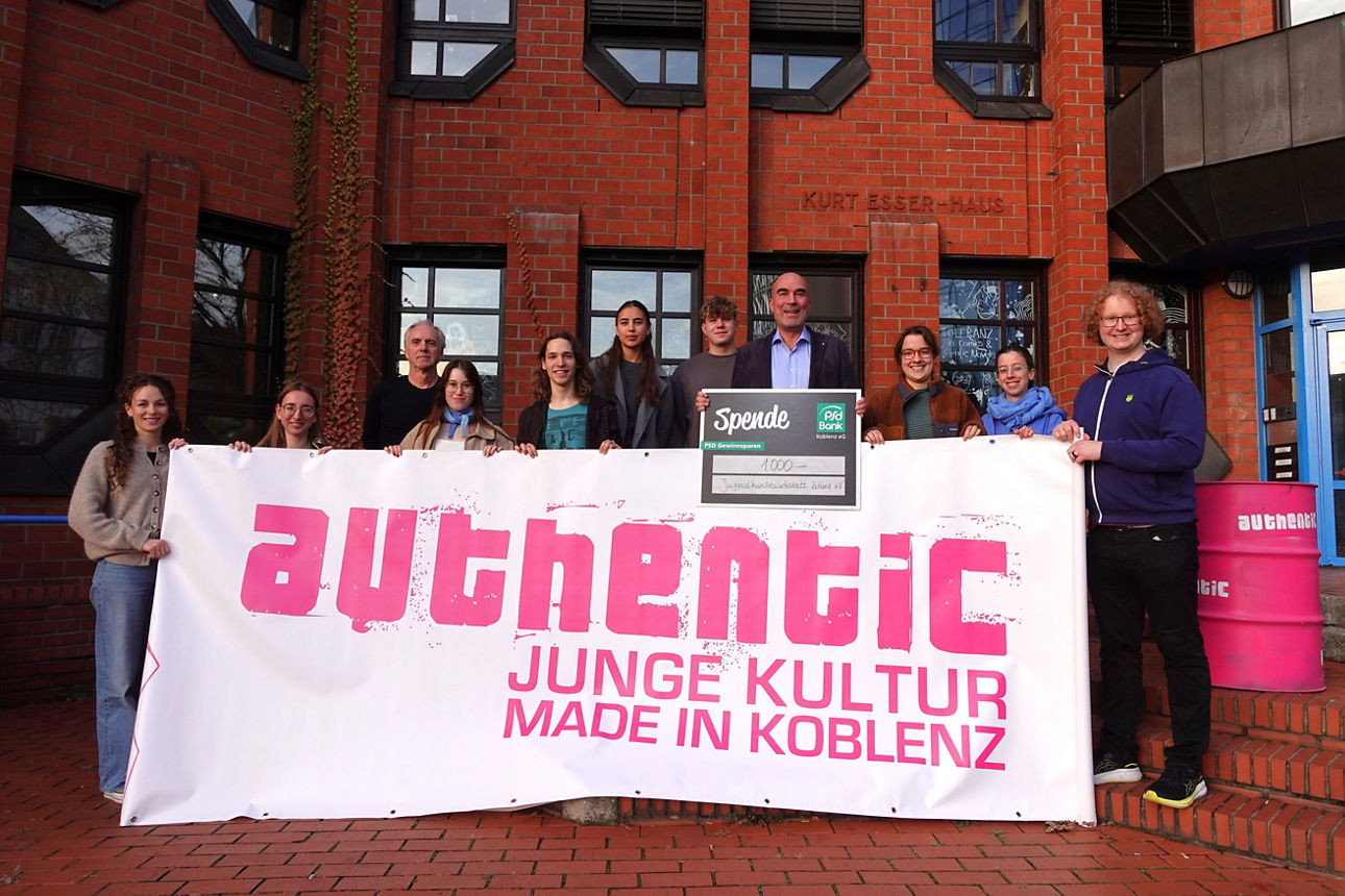 Eine Gruppe Personen posiert mit einem Spendenscheck