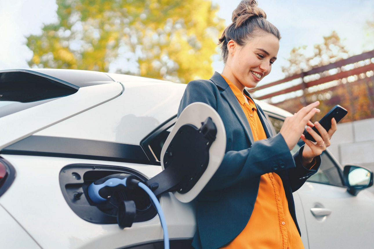 Frau an einem Elektroauto – passend zum Ratgeber über Autofinanzierung, Autokredit und Leasing.
