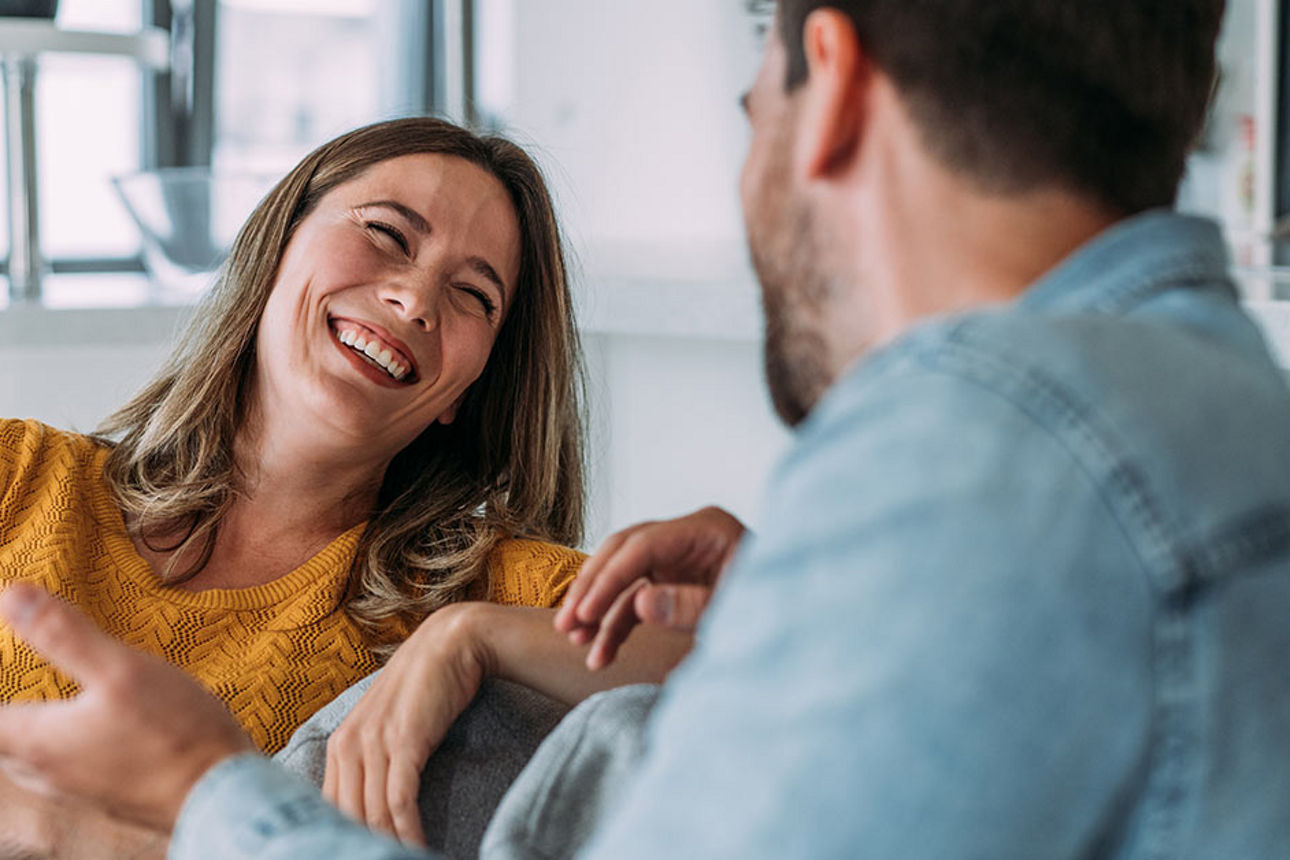 Frau und Mann lachend auf Couch