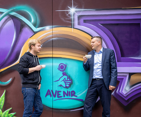 Zwei Männer mit Kaffee vor dem Avenir