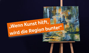 Ein Bild der Kunstauktion auf einer Staffelei vor einem schwarzen Hintergrund. Im Vordergrund steht der Slogan "Wenn Kunst hilft, wird die Region bunter".