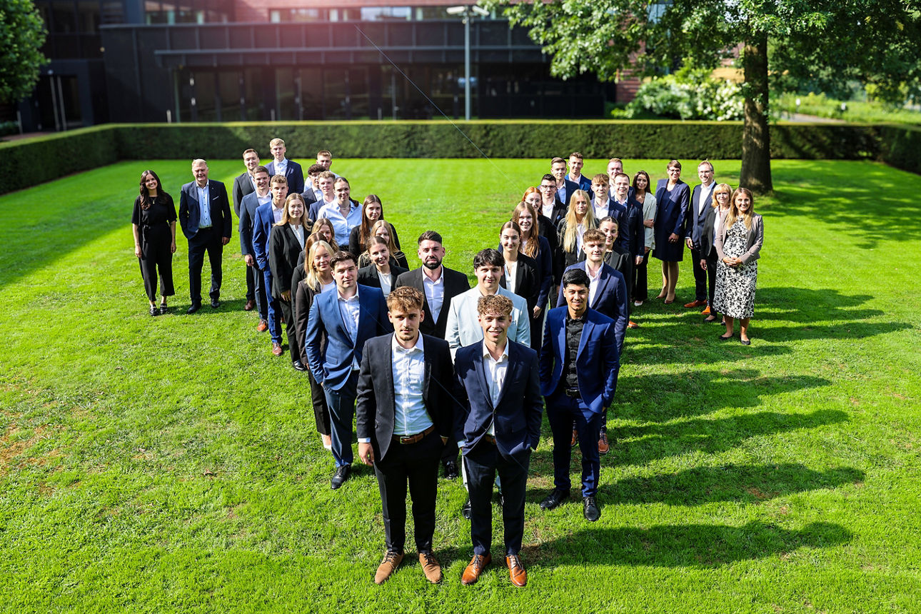 Eine Aufnahme eines Azubijahrgangs. Die Auszubildenden haben ein V geformt.