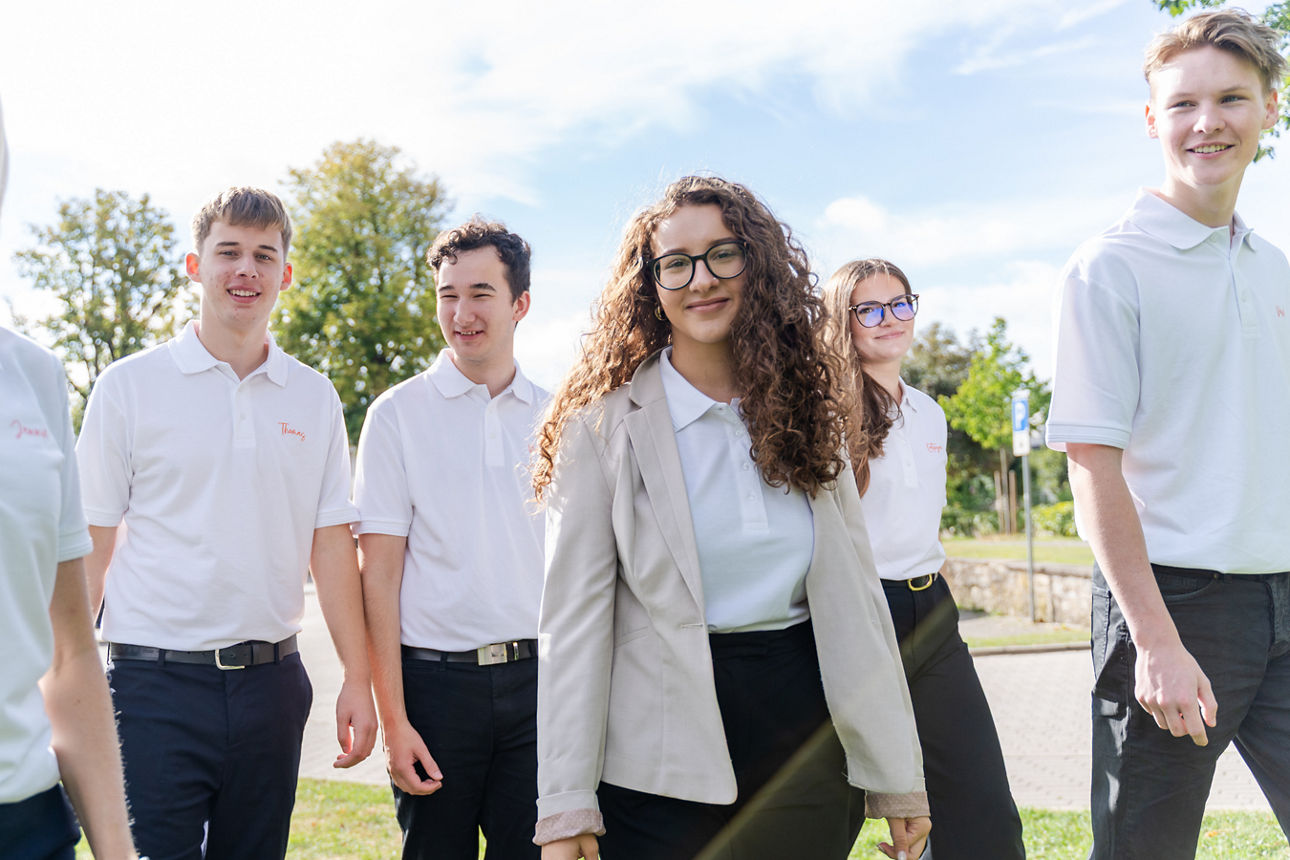 Azubis in weißer Kleidung, die sich draußen befinden