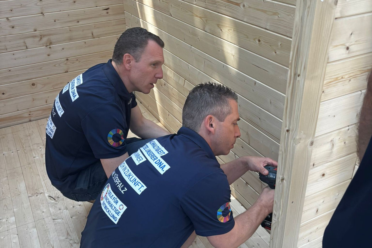 Zwei Männer bohren bei der Erstellung eines Holzhauses