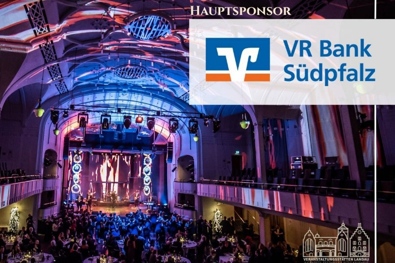 Ein Bild zeig die Festhalle von Innen mit dem VR Bank Südpfalz Logo sowie einem save the date Banner. 
