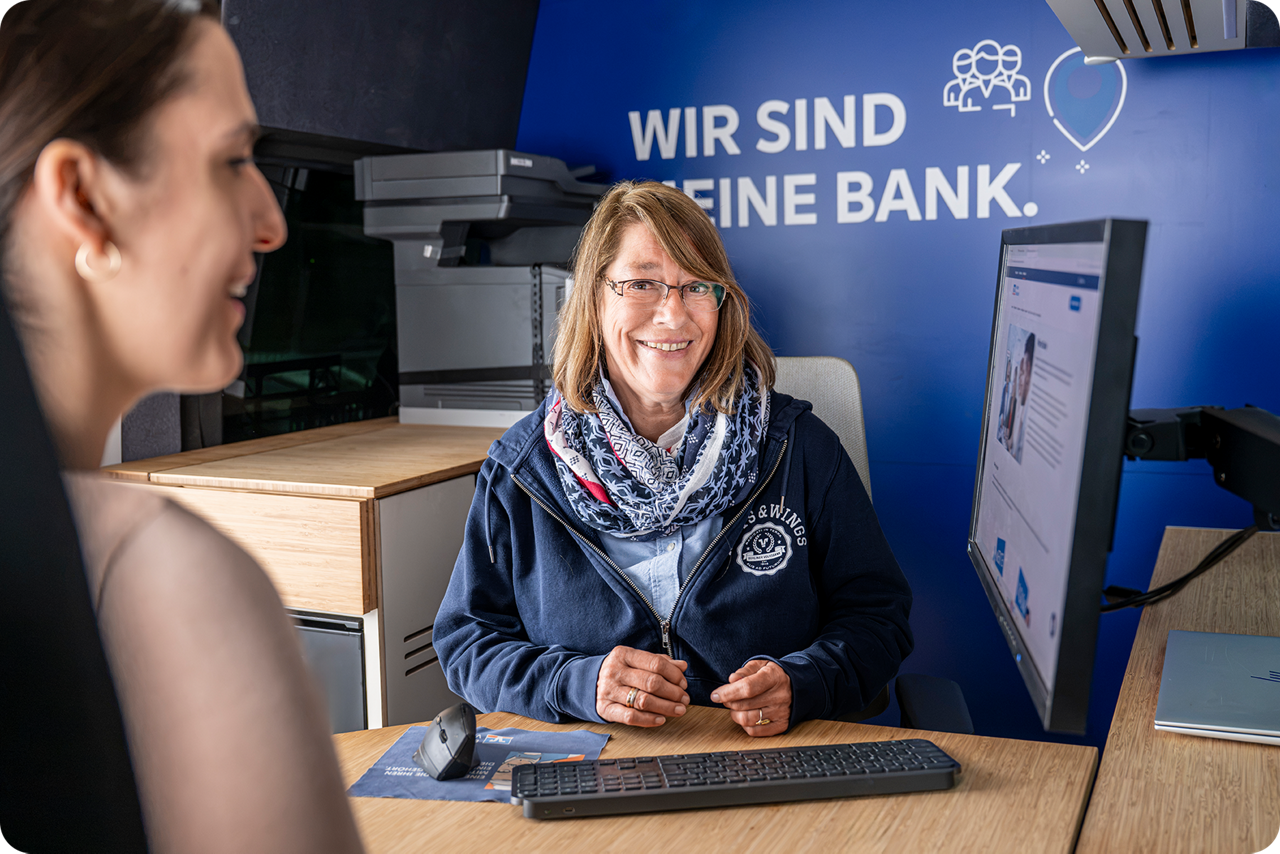 Zwei Frauen sitzen sich an einem Schreibtisch gegenüber und schaue gemeinsam auf einen Monitor