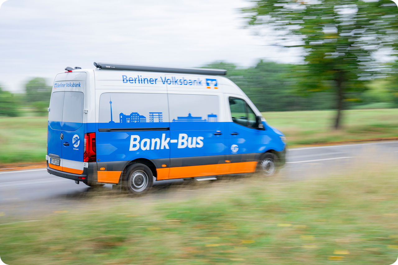 Ein blau orangener Kleintransporter fährt auf einer Straße 