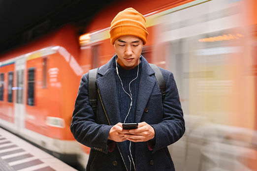 Mann in einer U-Bahn-Station, der auf sein Smartphone schaut