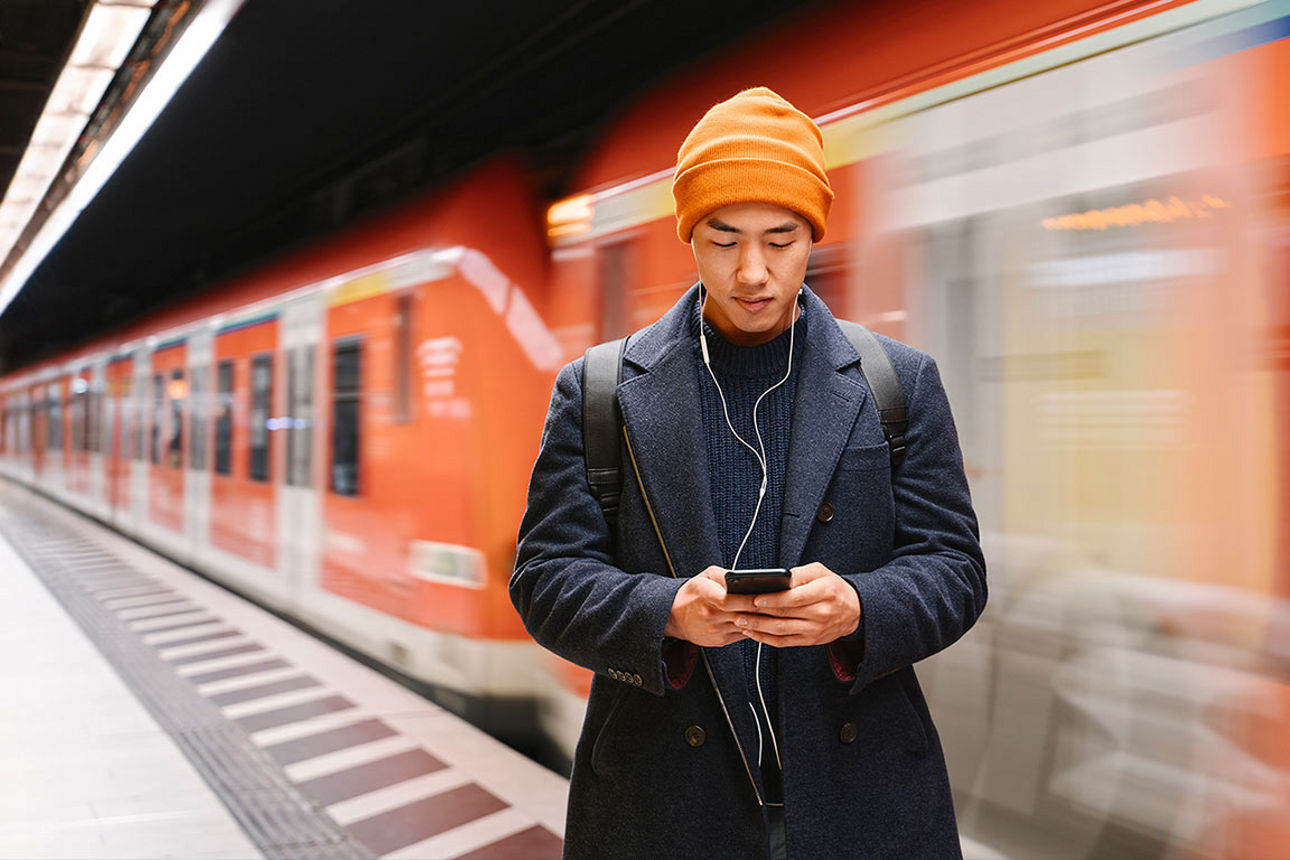 Mann in der U-Bahn, der auf sein Smartphone schaut