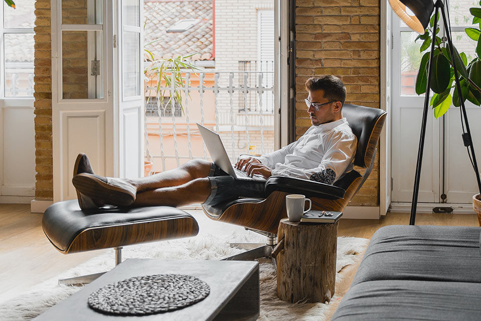 Ein Mann sitzt mit Laptop in einem Sessel