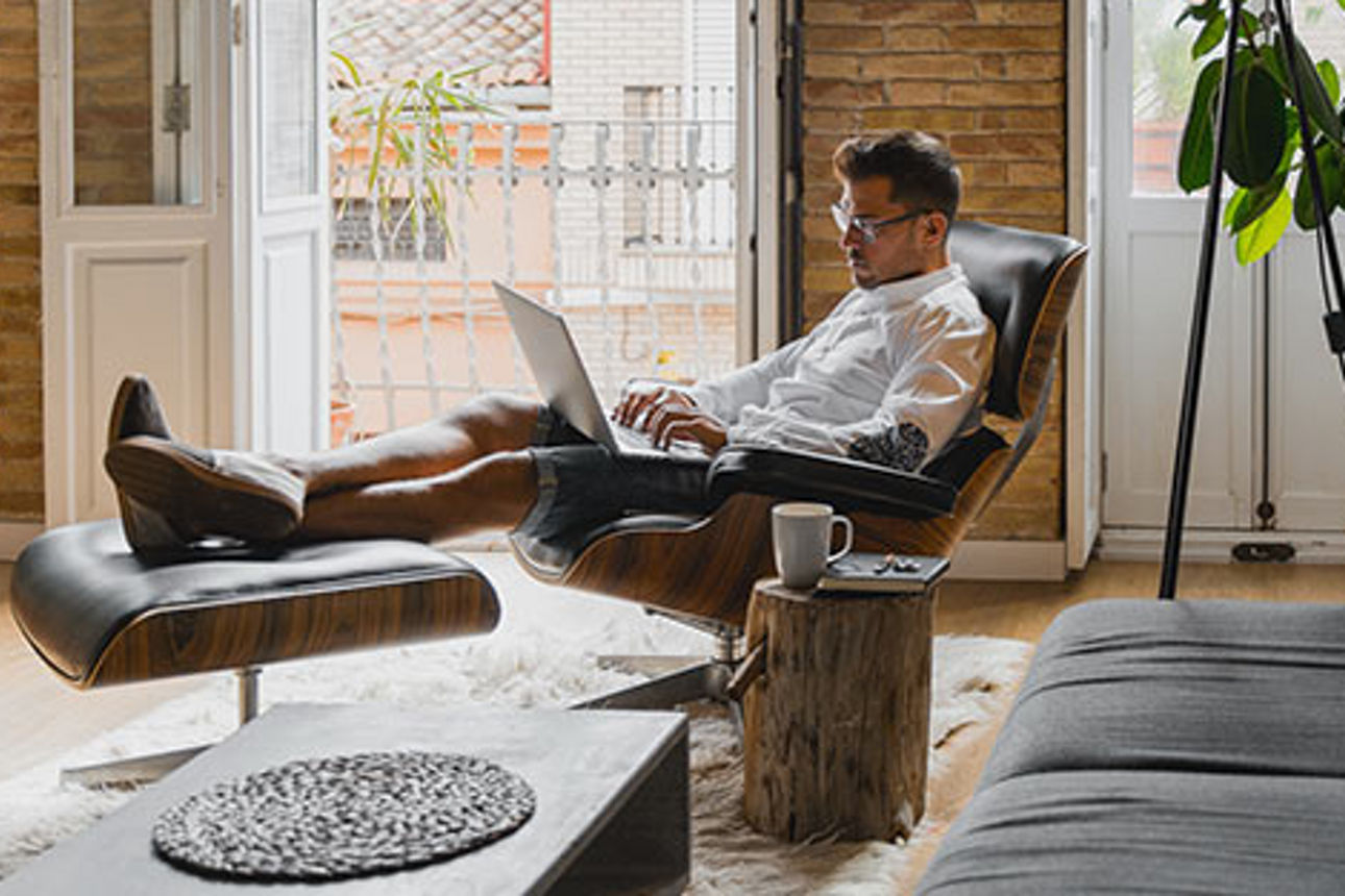 Ein Mann sitzt mit Laptop in einem Sessel