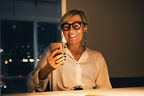 Eine Geschäftsfrau schaut lächelnd auf ihr Smartphone