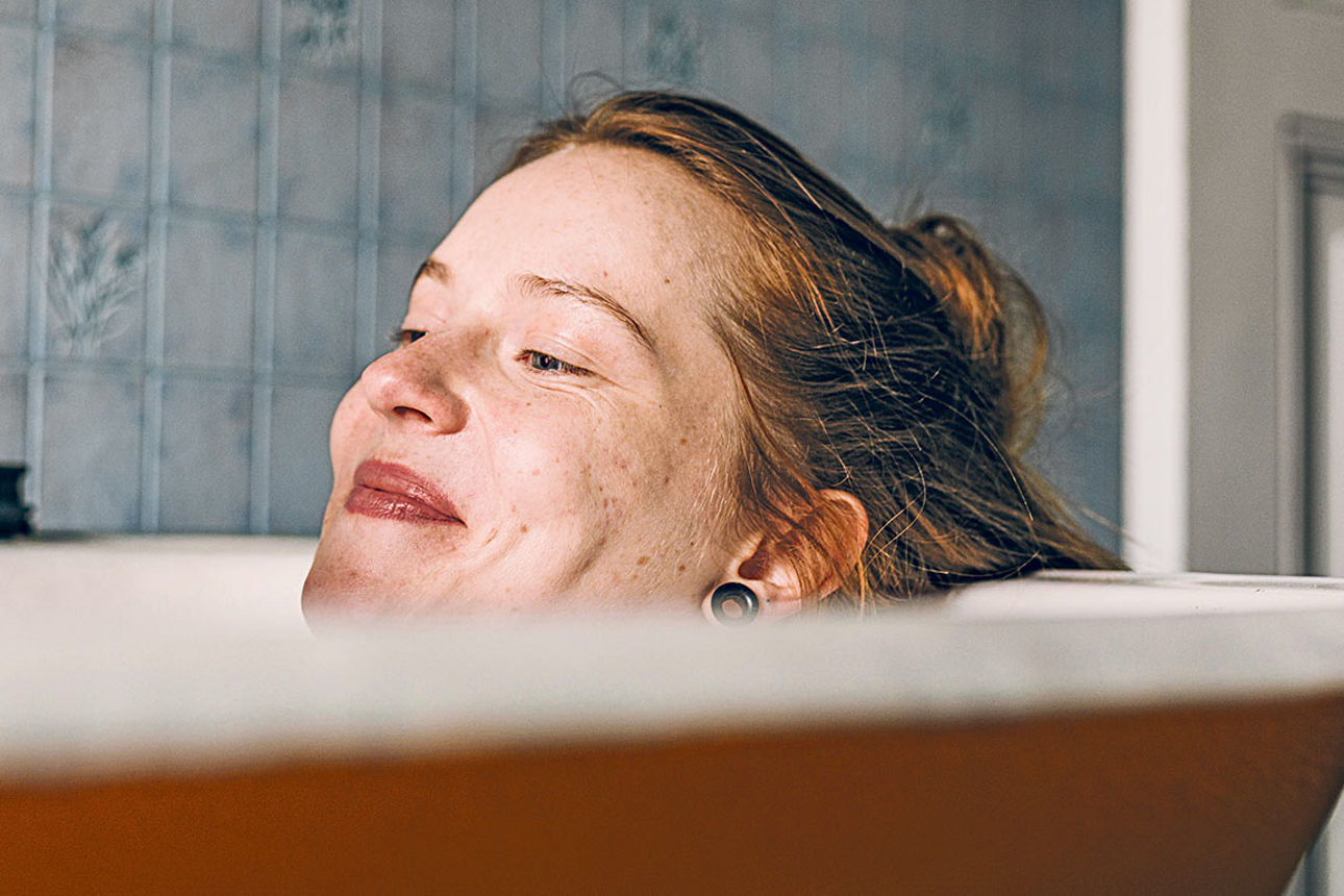 Eine Frau liegt in der Badewanne und schaut auf ihr Handy