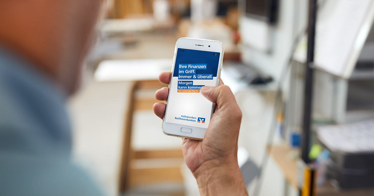 Mann hält sein Handy mit dem geöffneten OnlineBanking in der Hand