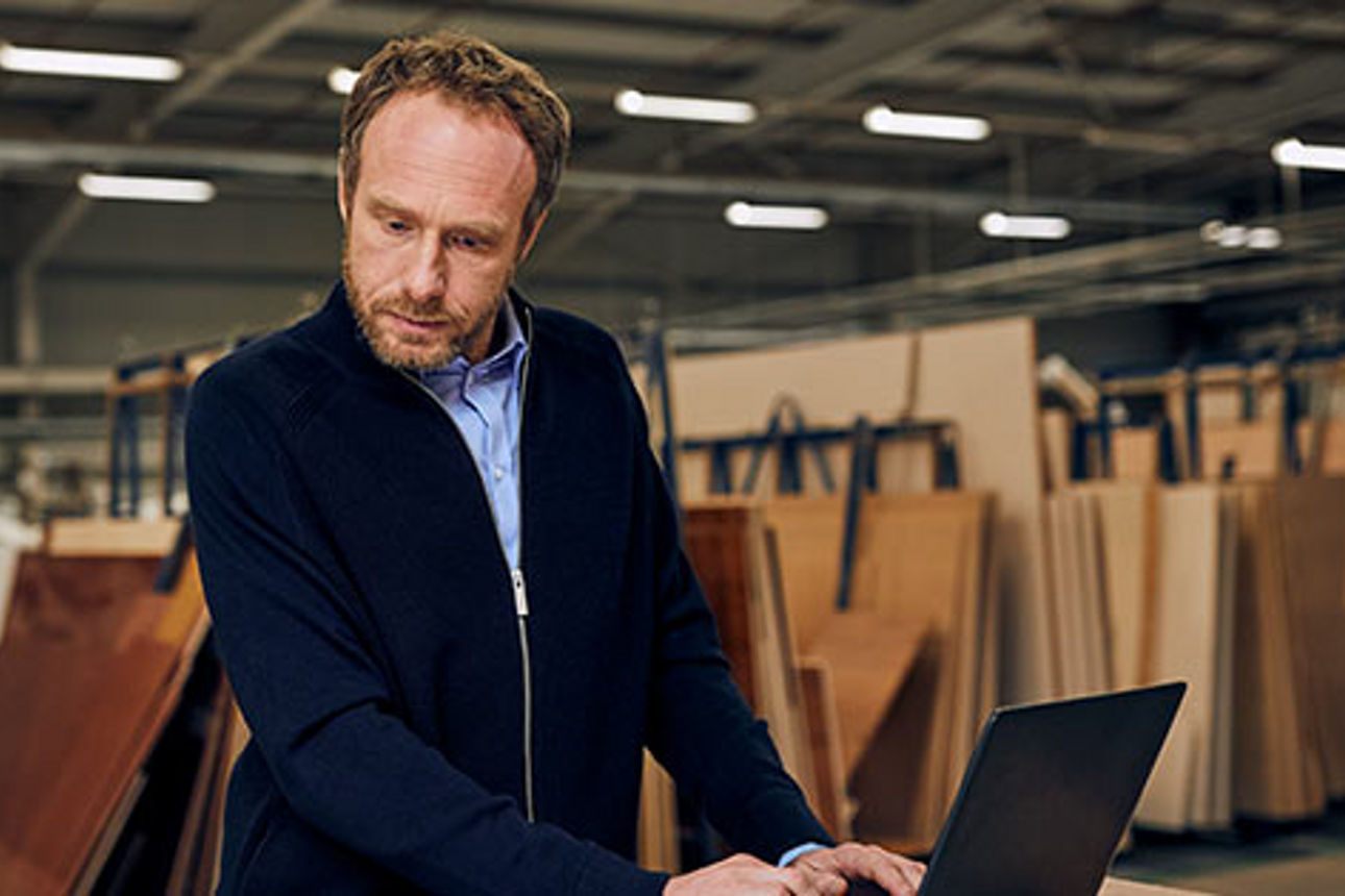 Ein Mann mit Schutzausrüstung bedient Maschinen in einer Fabrik.