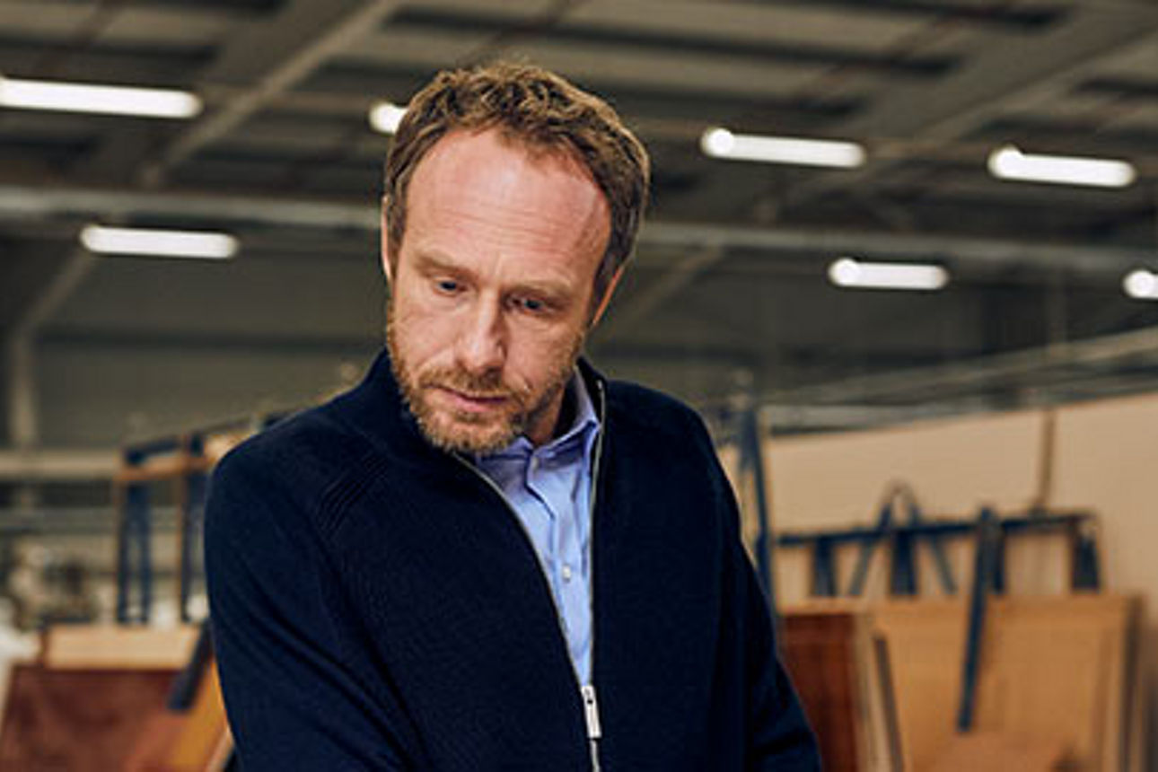 Ein Mann in einer Holzwerkstatt, der aufmerksam beobachtet, woran er gerade arbeitet