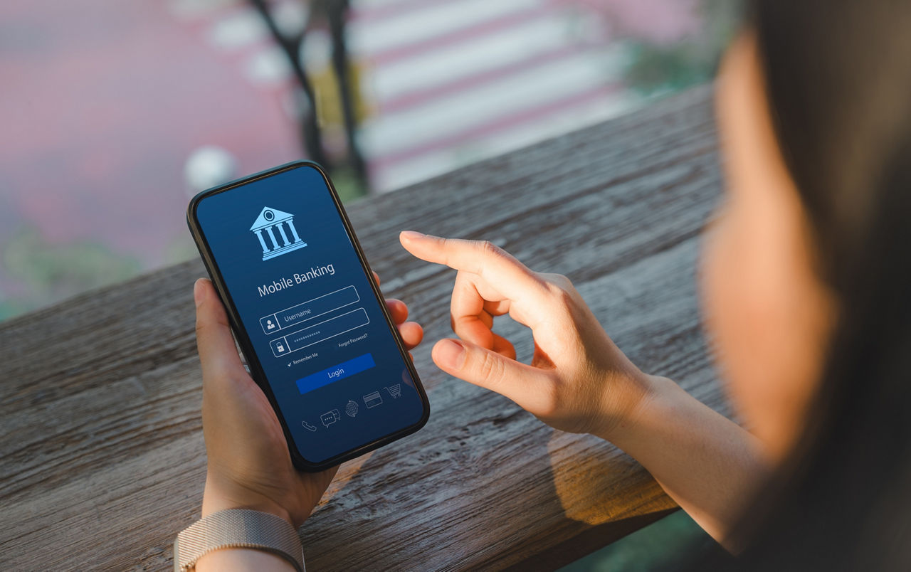 Online-Zahlungskonzept. Blick über die Schulter einer Frau, die auf ihrem Smartphone eine Mobile-Banking-App nutzt und die Ei