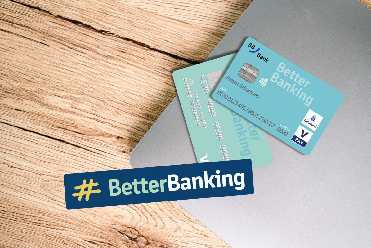 Person sitzt vor Laptop und zerschneidet Bankkarte mit einer Schere