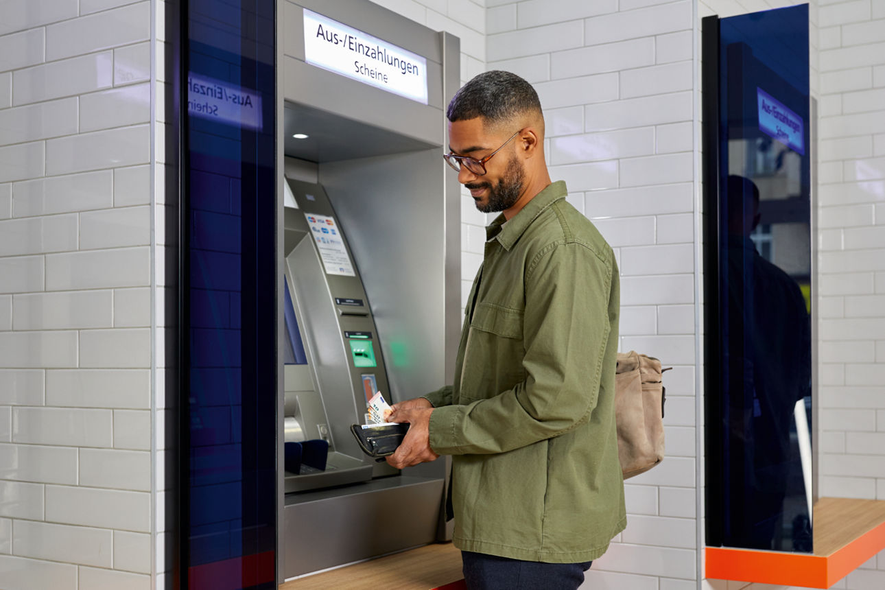 Ein Mann holt am Geldautomaten Geld ab.