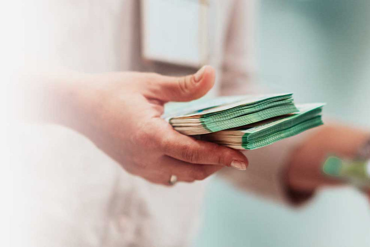 Geldver- und Endsorgung - Eine Person hält Geldbündel in der Hand