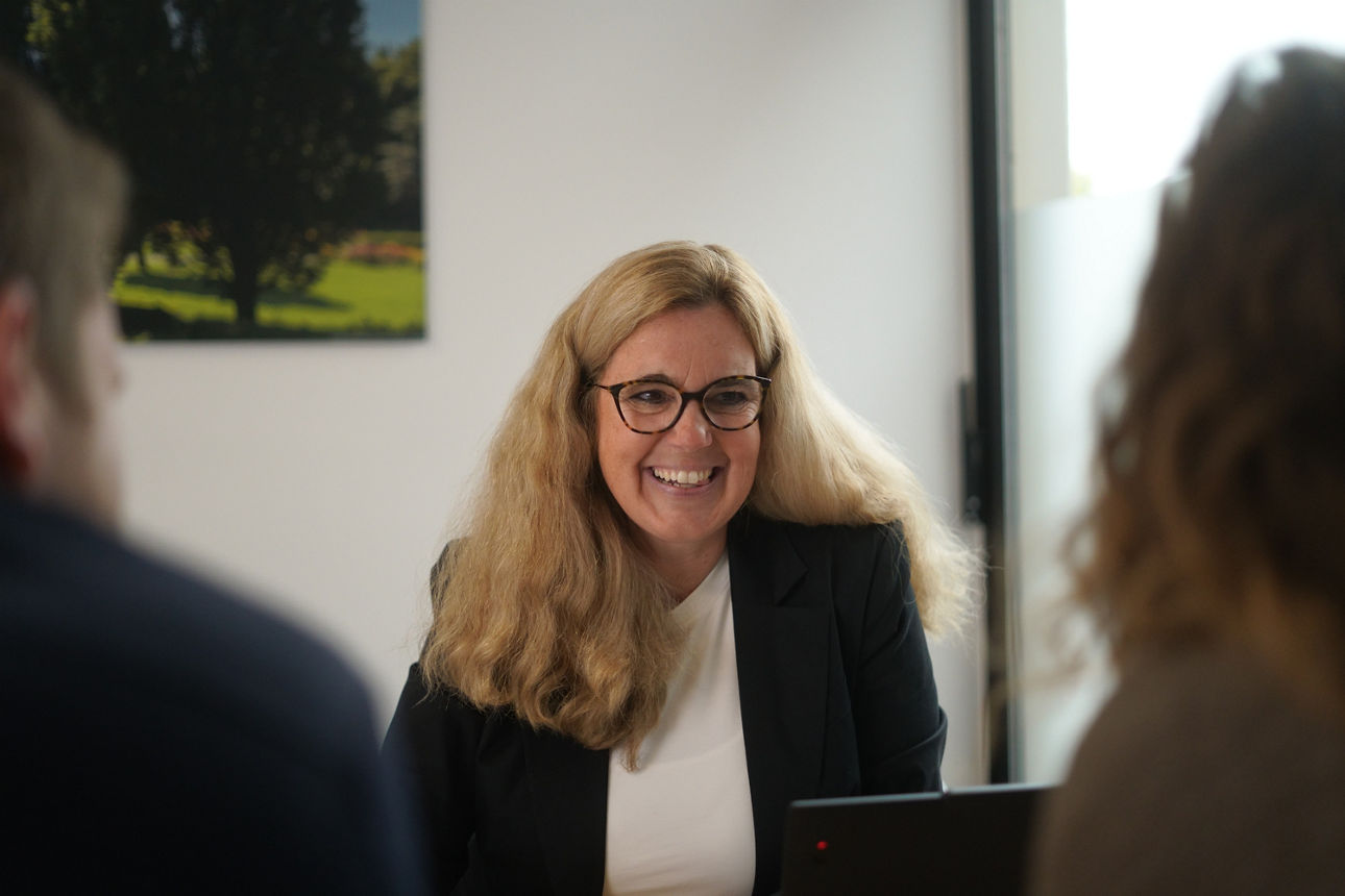 Eine blonde Frau lächelt im Beratungsgespräch