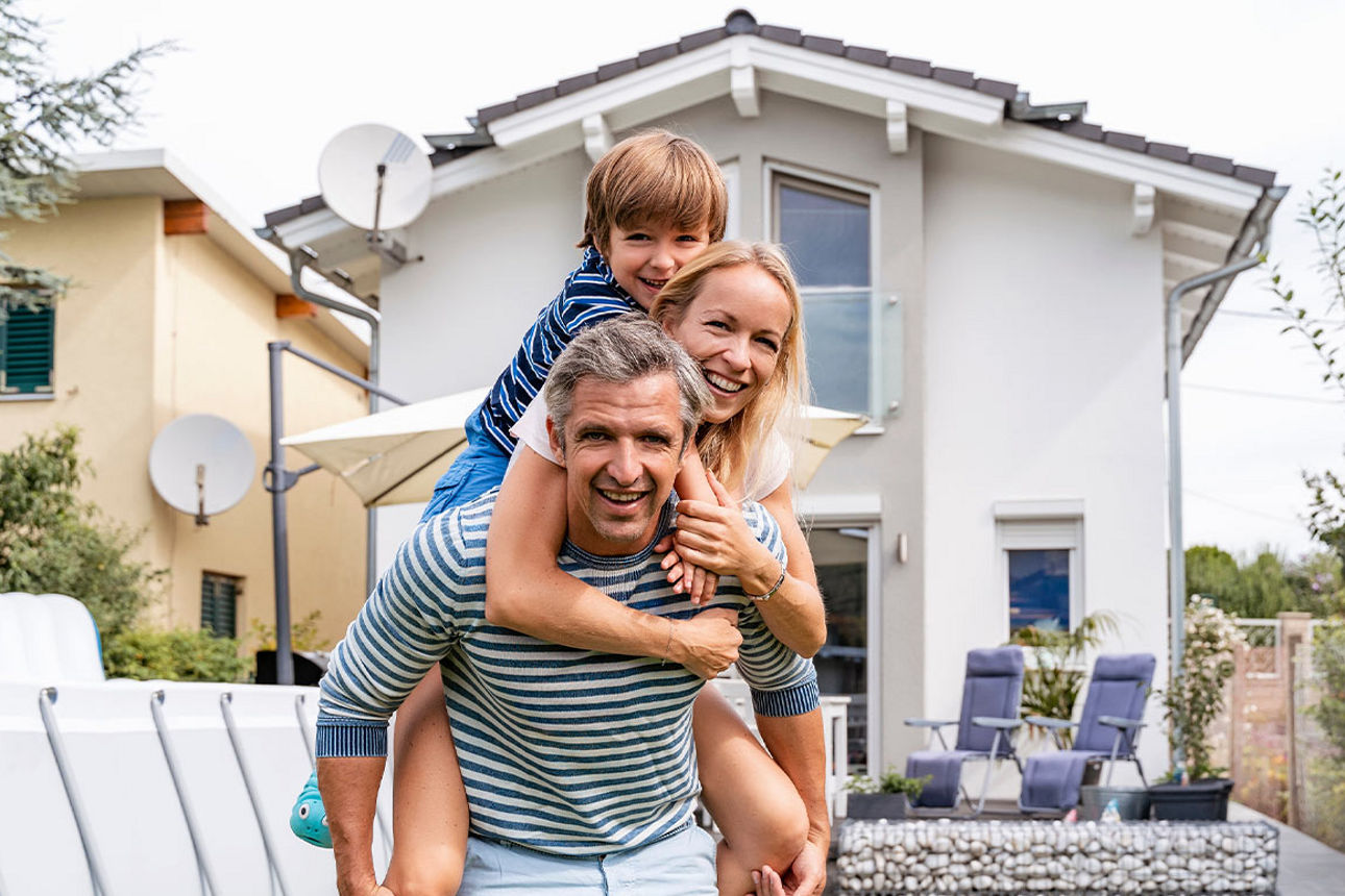 Eine Familie steht im Garten des Eigenheims