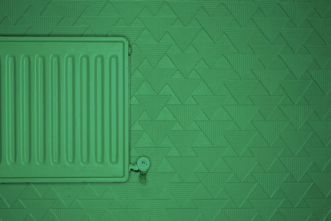 Eine grün lackierte Heizung vor einer grün gestrichenen Wand.