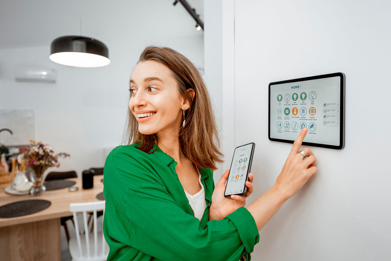 Eine junge Frau tippt auf einen Bildschirm an der Wand, um ihr Smart Home zu steuern