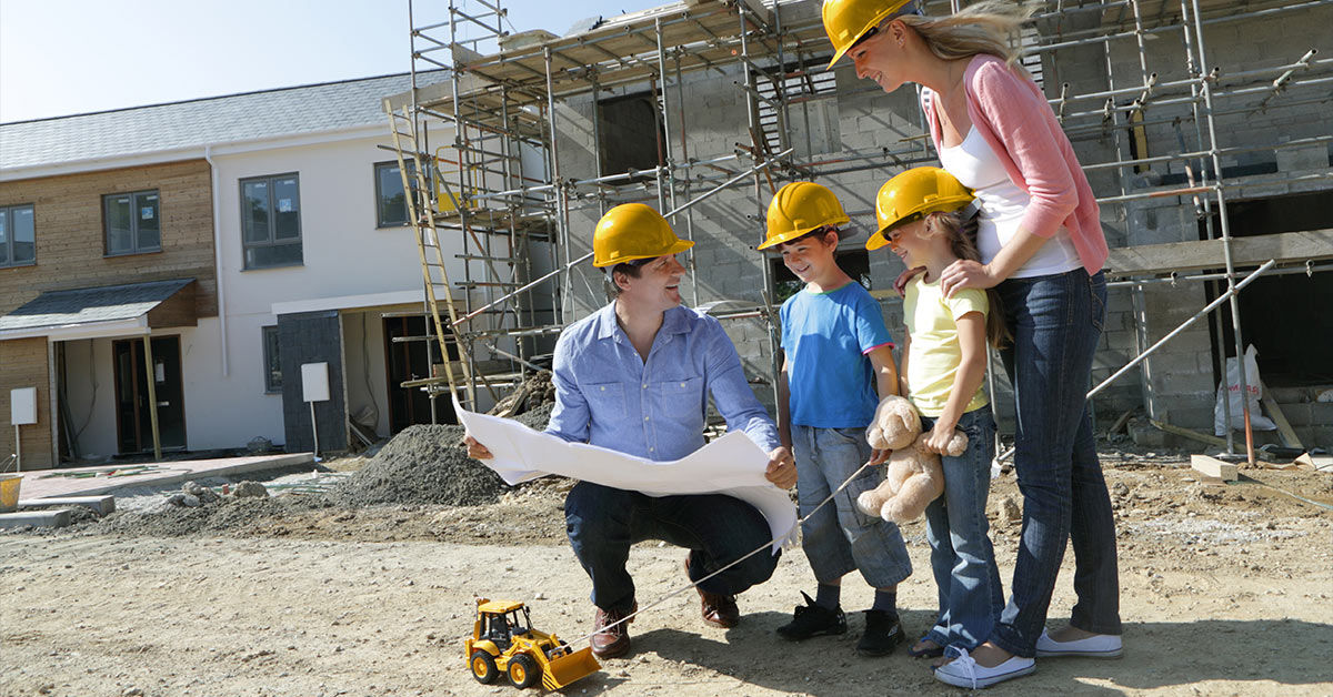 Familie schaut sich Bauplan Ihres Hauses auf Baustelle an