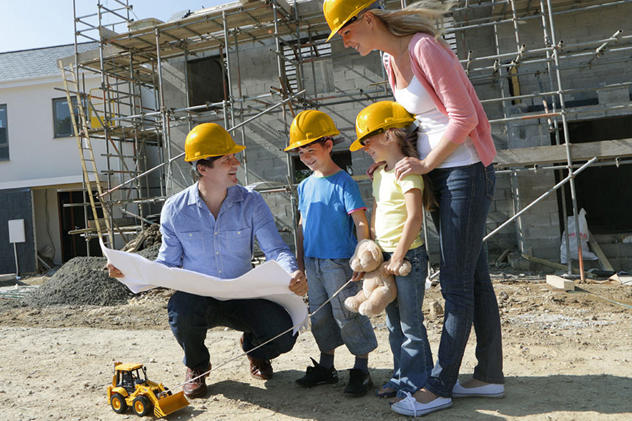 Familie schaut sich Bauplan Ihres Hauses auf Baustelle an